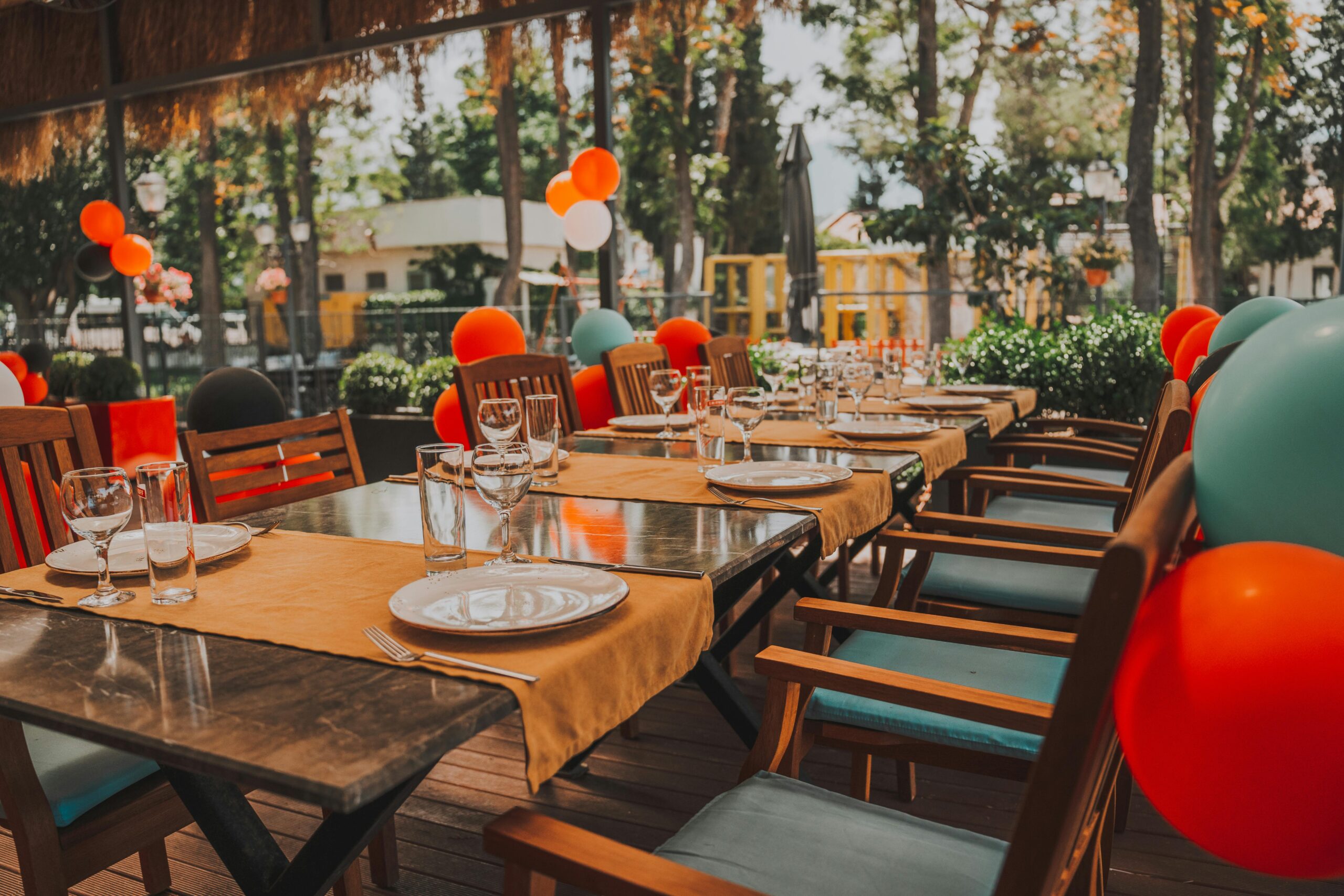 Outdoor table set for a celebration, adorned with colorful balloons creating a festive mood.